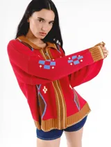 Campera tejida en jacquard de Anthea, en color rojo con detalles en marrón, celeste y blanco, con cuello solapa, cierre frontal y diseño de rombos.