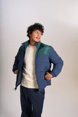 Campera puffer con diseño bicolor, cuerpo en azul marino y canesú superior en verde oscuro. Presenta cuello alto, cierre frontal completo y puños elásticos.