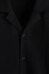 Camisa de manga corta negra H&M en punto jacquard de mezcla de algodón, con cuello abierto y cierre frontal de botones.