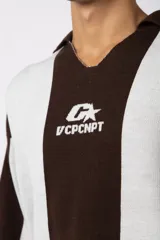 Sweater de tejido de punto con diseño de rayas verticales en tonos beige y blanco. Presenta cuello polo abierto, mangas largas y un corte holgado. Incluye un logo bordado en el centro del pecho.