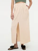 Falda maxi color beige de tiro alto, con diseño pinzado en la cintura, bolsillos laterales y tajo frontal pronunciado.
