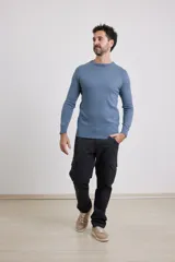 Sweater de tejido liso, color azul claro, con escote redondo y puños y ruedo acanalados.