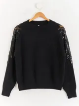 Sweater negro de tejido de punto con cuello redondo y mangas largas. Presenta detalles de transparencias y apliques bordados con pedrería en la parte superior de las mangas.