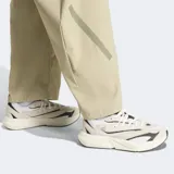 Pantalon Adidas Z.N.E. de corte holgado, confeccionado en tejido ripstop color beige. Presenta cintura elástica con cordón de ajuste, bolsillos laterales con cierre y detalles de estampado en caucho mate.