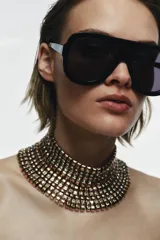 Maxi collar tipo choker de diseño rígido y estructurado, compuesto por múltiples filas de piezas metálicas doradas intercaladas con pequeñas incrustaciones de cristales brillantes.