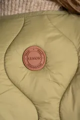 Chaleco acolchado color verde oliva, con diseño capitoneado de ondas, cierre frontal con botones y bolsillos laterales.