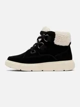 Bota de caña media con diseño tipo botín, confeccionada en gamuza impermeable color negro. Presenta un ribete superior de borrego sintético en color crema, cordones gruesos con herrajes metálicos y una suela de goma moldeada en color crema con excelente tracción.