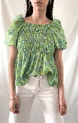 Blusa verde con estampado floral en tonos celeste y marrón, escote cuadrado con elástico, mangas cortas abullonadas y cuerpo fruncido.
