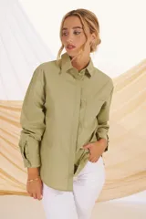Camisa verde militar de corte holgado, con cuello clásico, cierre frontal con botones, bolsillo de parche en el pecho y mangas largas con puños abotonados.