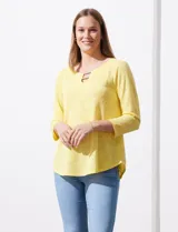 Blusa amarilla de tejido labrado con cuello redondo, escote en V y aplique metálico.