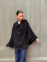 Capa negra de tejido de punto en lana con apliques de cuero y cuello drapeado.