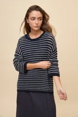 Sweater de tejido amplio en color azul marino con diseño de rayas horizontales y detalles calados. Cuenta con cuello redondo, mangas largas con hombros caídos y terminaciones acanaladas.