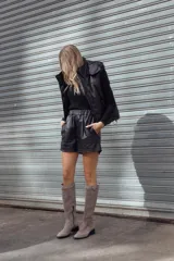 Bota de caña alta color arena, confeccionada en gamuza italiana impermeabilizada y forrada en cuero. Presenta un estribo con aplique metálico y base ultraliviana con taco de 3,5 cm.