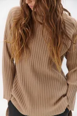 Polera de tejido de punto acanalado en color negro, con cuello alto y diseño de corte recto con largo asimétrico, más corto adelante y más largo atrás.