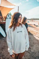 Buzo color crudo con cuello redondo y puños y cintura acanalados. Estampado en la espalda con diseño de palmera y texto enmarcado en damero.