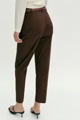 Pantalón tobillero de tiro medio, color azul marino, con bolsillos delanteros y cierre frontal con cremallera, botón y gancho. Incluye un cinturón fino de color marrón con hebilla metálica.