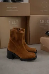 Bota de caña media con punta cuadrada, confeccionada en cuero gamuzado color marrón, con taco bloque y suela de goma negra.