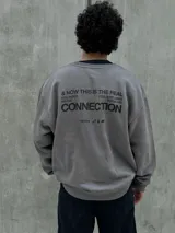 Buzo gris con cuello redondo, mangas largas y puños y bajo acanalados. Estampado frontal con el logo "Osten" y la frase "A mindset of becoming".