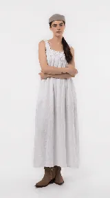 Vestido largo de lino color blanco, de silueta amplia, con escote cuadrado fruncido y breteles anchos con detalles de volados.