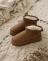 Botas tipo pantubota color marrón claro, con interior forrado en piel sintética blanca, suela de plataforma plana y cierre lateral.