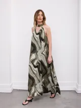 Vestido largo en tono verde militar, con estampado de efecto marmolado, escote halter y cuello alto.