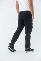 Pantalón cargo de corte slim, color negro, con bolsillos laterales con solapa y botones metálicos. Cuenta con cierre frontal, botón en la cintura y pasacintos.