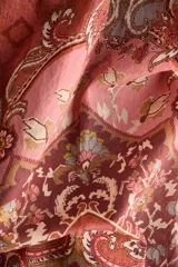 Camisa de manga larga confeccionada en gasa de algodón con estampado tipo paisley y motivos ornamentales en tonos rojizos y rosados. Presenta cuello clásico, cierre frontal con botones y puños abotonados.