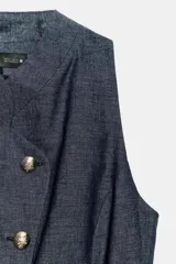 Chaleco cruzado confeccionado con lino de color azul marino, con cuello redondo, manga sisa, bajo con pinzas y cierre frontal con botones dorados.