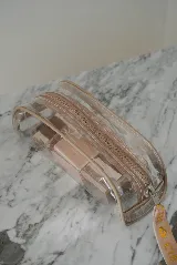 Necessaire transparente de PVC con cierre y bordes en color beige, ideal para guardar artículos pequeños de maquillaje o cuidado personal.