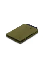 Billetera plegable de cuero color marrón claro, con costuras blancas visibles en los bordes. Presenta un pequeño logo grabado en la parte inferior derecha y una abertura rectangular cosida en la parte superior central. En el lateral derecho se aprecian detalles de tela con los colores de la bandera francesa (azul, blanco y rojo).