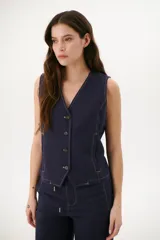Chaleco sin mangas color azul marino, con escote en V y cierre frontal de botones. Presenta costuras visibles en contraste de color claro, simulando bolsillos falsos o detalles de sastrería.