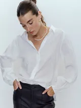 Camisa blanca de mangas largas con puños abullonados y cuello clásico.