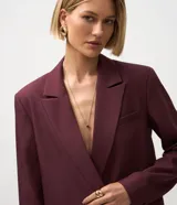 Blazer femenino color bordó, de corte oversized y caída recta. Presenta cierre traspasado con dos botones delanteros, mangas largas, cuello con solapa tradicional y bolsillos delanteros con acabado incorporado. Cuenta con forro interno.