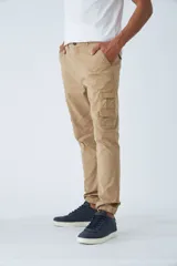 Pantalón cargo de hombre con fit slim, confeccionado en una mezcla de algodón y elastano. Presenta cierre de cremallera y botón, bolsillos laterales tipo cargo, pasa cinto y terminación con puños elásticos en los tobillos.