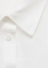 Camisa de lino blanca con cuello camisero, cierre frontal de botones, manga larga y bolsillo aplicado en el pecho.
