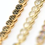 Pulsera dorada de eslabones con corazones cubiertos de cristales negros.