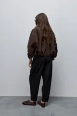 Pantalón marrón de tiro alto y silueta amplia, confeccionado con pinzas en el frente y bolsillos laterales.