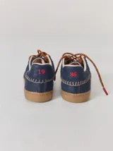 Championes urbanos de cuero con diseño de paneles en color negro y marrón. Presentan cordones trenzados, costuras a la vista y detalle de refuerzo en el talón con pespuntes decorativos.