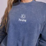 Buzo de cuello redondo con efecto de lavado desgastado, color azul. Presenta un pequeño bordado gráfico en el pecho con el logo de la marca.