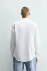 Camisa de corte slim fit confeccionada en tejido de algodón con textura. Presenta cuello italiano, manga larga con puños abotonados y cierre frontal de botones.