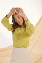 Camisa verde lima de manga larga con puños abullonados y botones dorados.