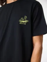 Camiseta negra de corte regular fit, confeccionada en algodón orgánico. Presenta un pequeño estampado en color verde lima en el pecho con un diseño de oruga y texto en inglés y japonés.