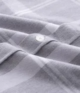 Camisa de franela de manga larga con estampado de cuadros en blanco y negro. Presenta cuello inglés, cierre frontal con botones y bolsillo en el pecho.