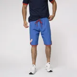 Short de baño azul con cintura elastizada, cordón de ajuste rojo, logo del Club Nacional de Football estampado en la pierna izquierda y ribete rojo en el ruedo.