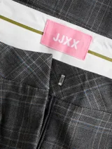 Pantalón sastrero de tiro alto y corte wide leg, con diseño de cuadros en tonos gris oscuro. Presenta cierre frontal con cremallera y bolsillos laterales.