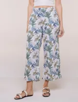 Pantalón crop de lino y rayón, con diseño wide leg de corte holgado, estampado tropical de hojas en tonos verde, azul y marrón sobre fondo blanco. Cuenta con pretina trasera elastizada y bolsillos delanteros.