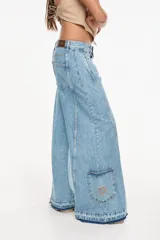 Jean de denim celeste de tiro alto y silueta wide leg, con costuras marcadas, bolsillos funcionales, bolsillo trasero inferior con bordado y terminación desflecada en el ruedo.