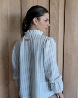 Blusa de algodón con cuello mao y volados, mangas largas con puños elásticos y corte holgado.