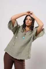 Blusa verde oliva de lino con cuello redondo, mangas cortas amplias con flecos, cierre lateral con botones y ruedo con flecos.