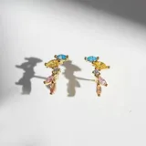 Par de aros dorados con piedras engarzadas de colores azul, amarillo, rosa, coral y blanco.